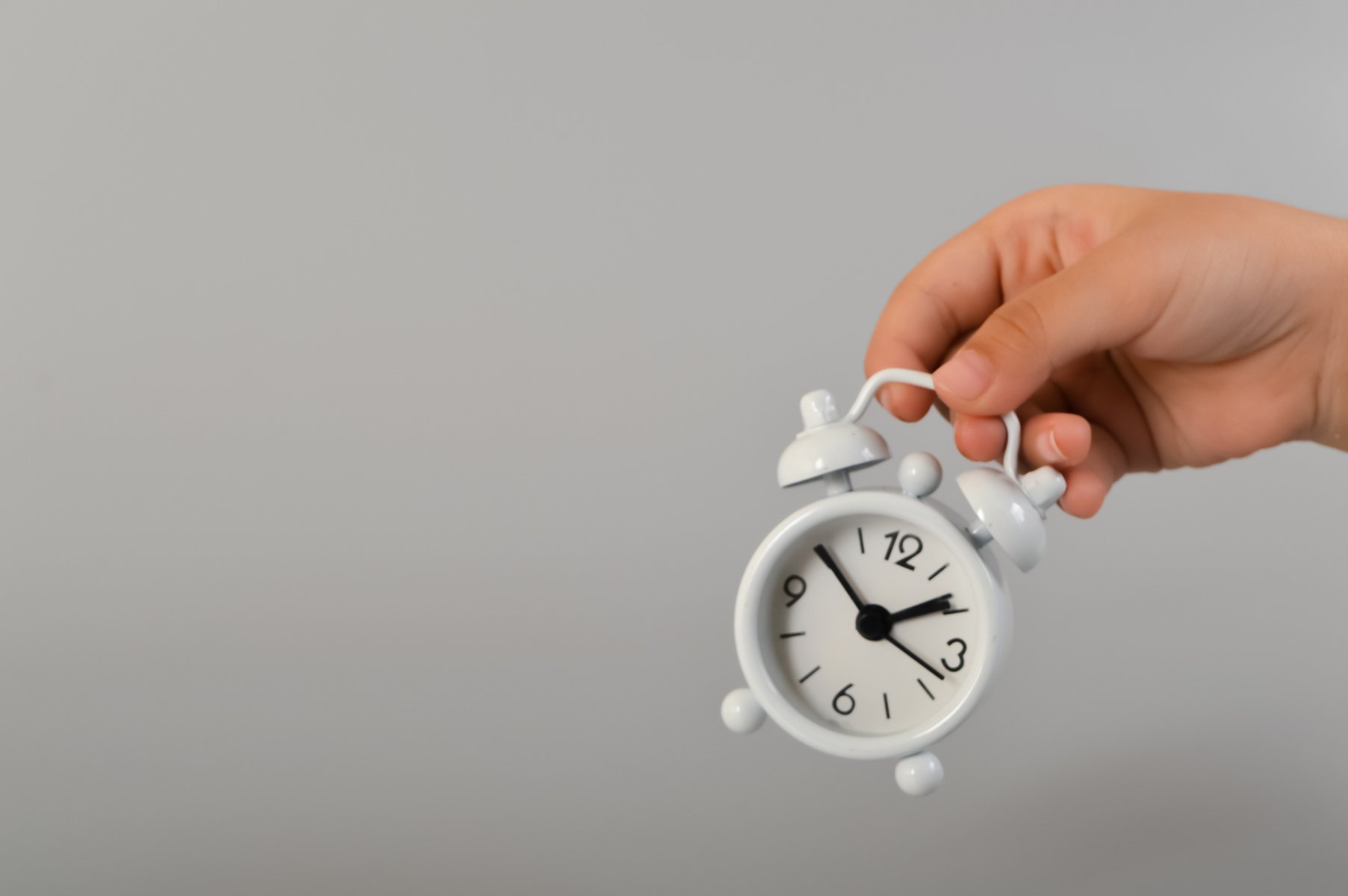 Hand holding white clock. Time concept.